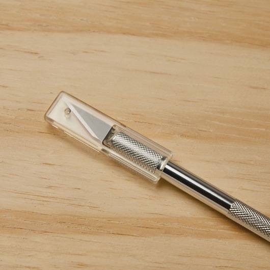 STANLEY 10-401 precision hobby knife with silver textured handle and clear safety cap, photography on wood surface.