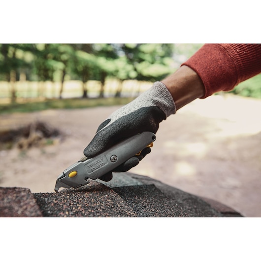 Stanley 10-499 utility knife being used on roofing material outdoors, close-up side angle.