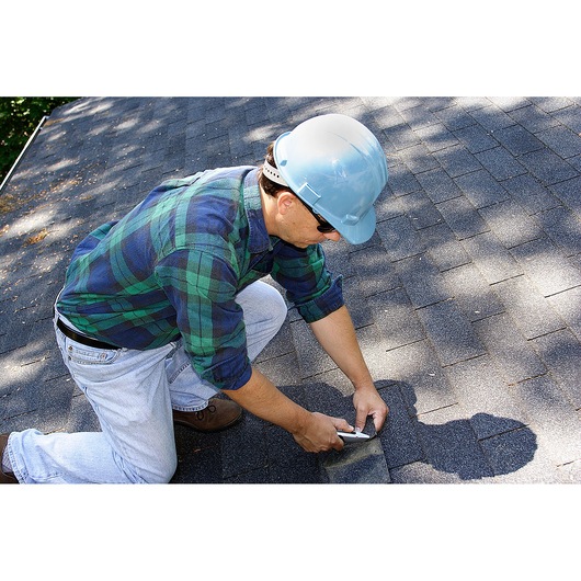 STANLEY 10-789 utility knife in use on roof shingles, person kneeling and cutting roofing material.