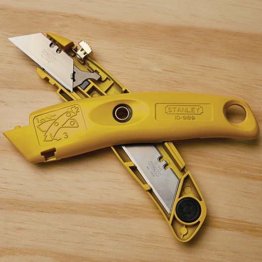 STANLEY 10-989 yellow utility knife open to show spare blade storage on wooden surface.