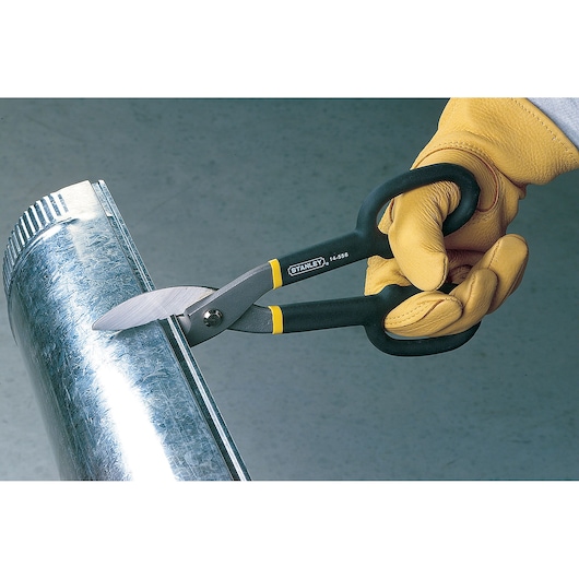Stanley 14-556 metal cutting snips in use, black and yellow handles, cutting galvanized pipe.