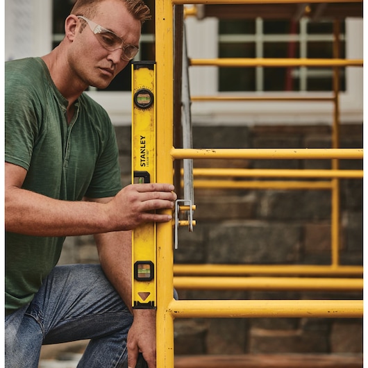 Stanley 42-324 level tool held against yellow scaffolding outdoors, product photography.