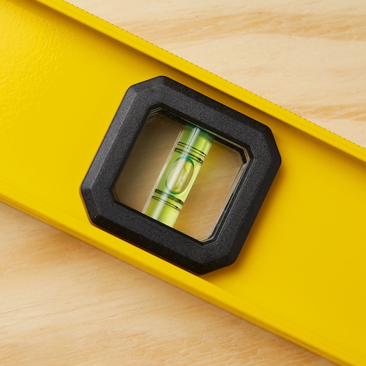 STANLEY 42-324 yellow spirit level with center vial, close-up photo on wood surface.