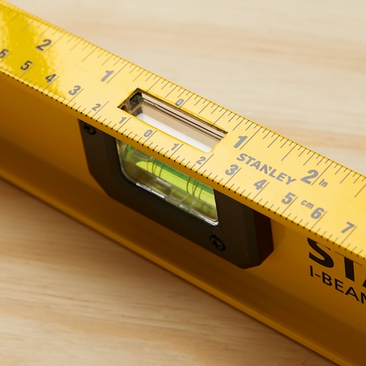 STANLEY 42-324 yellow I-beam level with built-in ruler, close-up of vial and measurement markings.