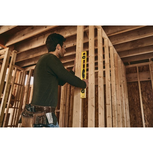 STANLEY 42-468 level tool used by worker in unfinished wood frame structure, side angle photo.