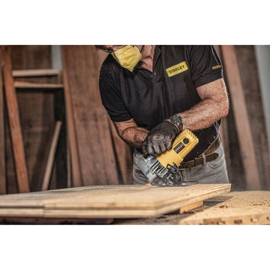 STANLEY SC16 circular saw cutting wood, photography of user wearing gloves and mask in workshop.