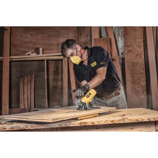 STANLEY SC16 circular saw in use cutting plywood, worker wearing protective gear in workshop.