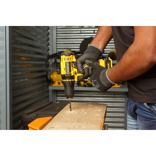 STANLEY SCD20C2K cordless drill in use on wood, yellow and black design, close-up side angle.