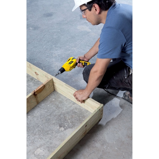 STANLEY STDR5206 drill in use on wooden frame, worker holding tool on concrete floor, side view.
