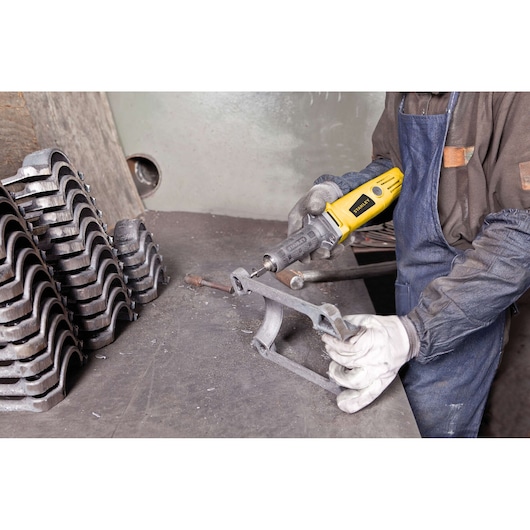 STANLEY STEL861 rotary tool used on metal part in workshop, person wearing gloves and apron.