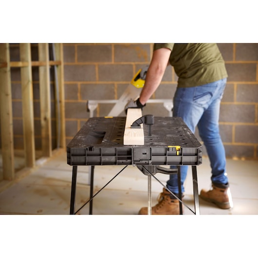 STANLEY STST11552 workbench with wood clamped, photo of product in use in construction setting.