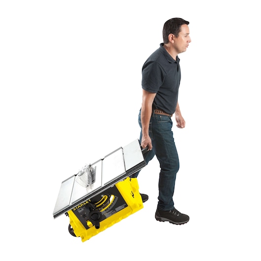 STANLEY STST1825 portable table saw being carried by a person, side angle, yellow base, white background.