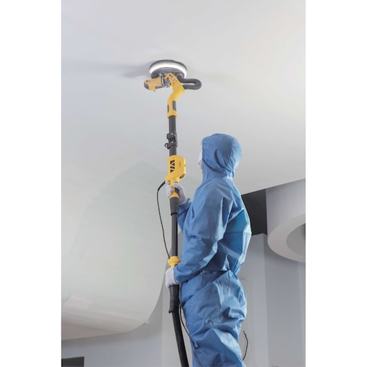 STANLEY SW75-BR drywall sander in use, person in blue suit sanding white ceiling, photography side angle