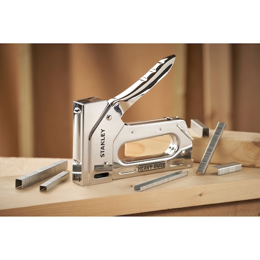 STANLEY TR110 heavy-duty staple gun with chrome finish, shown with staples on wood surface, angled view.
